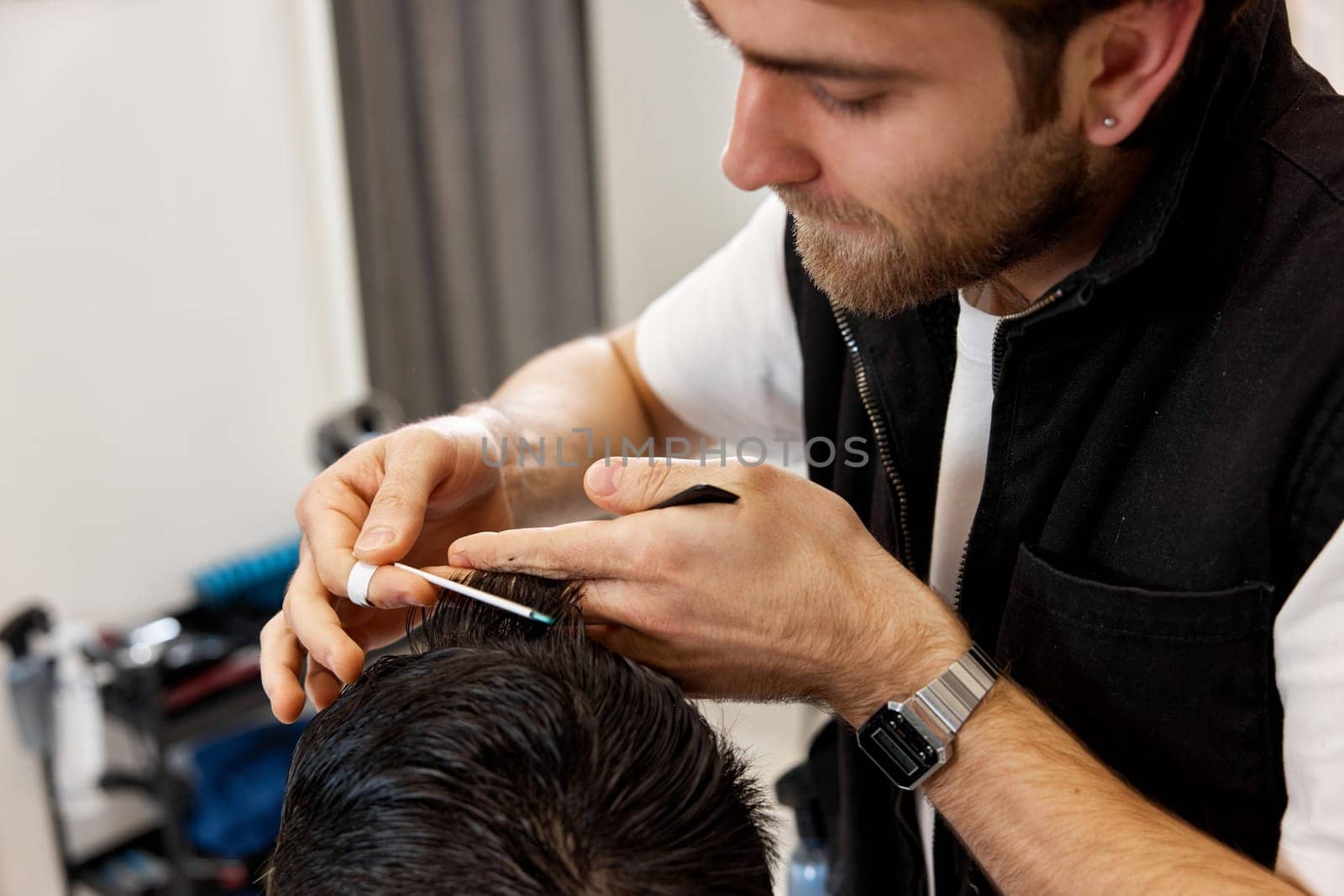 close-up, professional hairstylist does haircut for caucasian client man at barber shop.