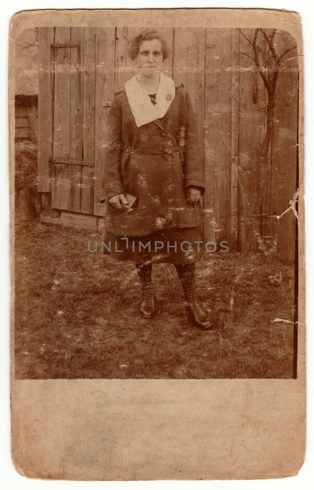 Vintage photo shows rural woman poses outside. Retro black and white photography with sepia effect. by roman_nerud