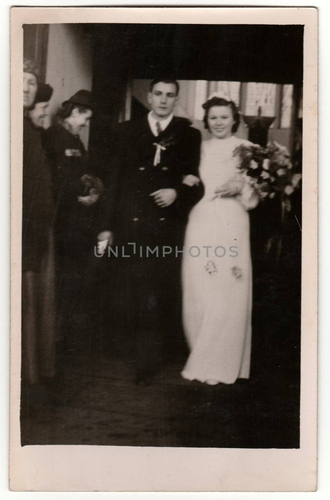 PRAGUE, THE CZECHOSLOVAK REPUBLIC - MARCH 9, 1940: Vintage photo shows newlyweds. Wedding ceremony - bride and groom go from church/cathedral. Retro black and white photography with sepia effect.