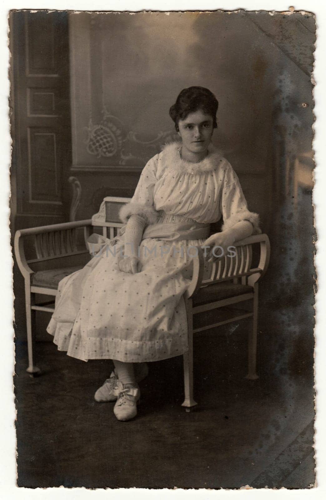 GERMANY - CIRCA 1920s: Vintage photo shows woman sits on a white period bench. Retro black and white studio photography.
