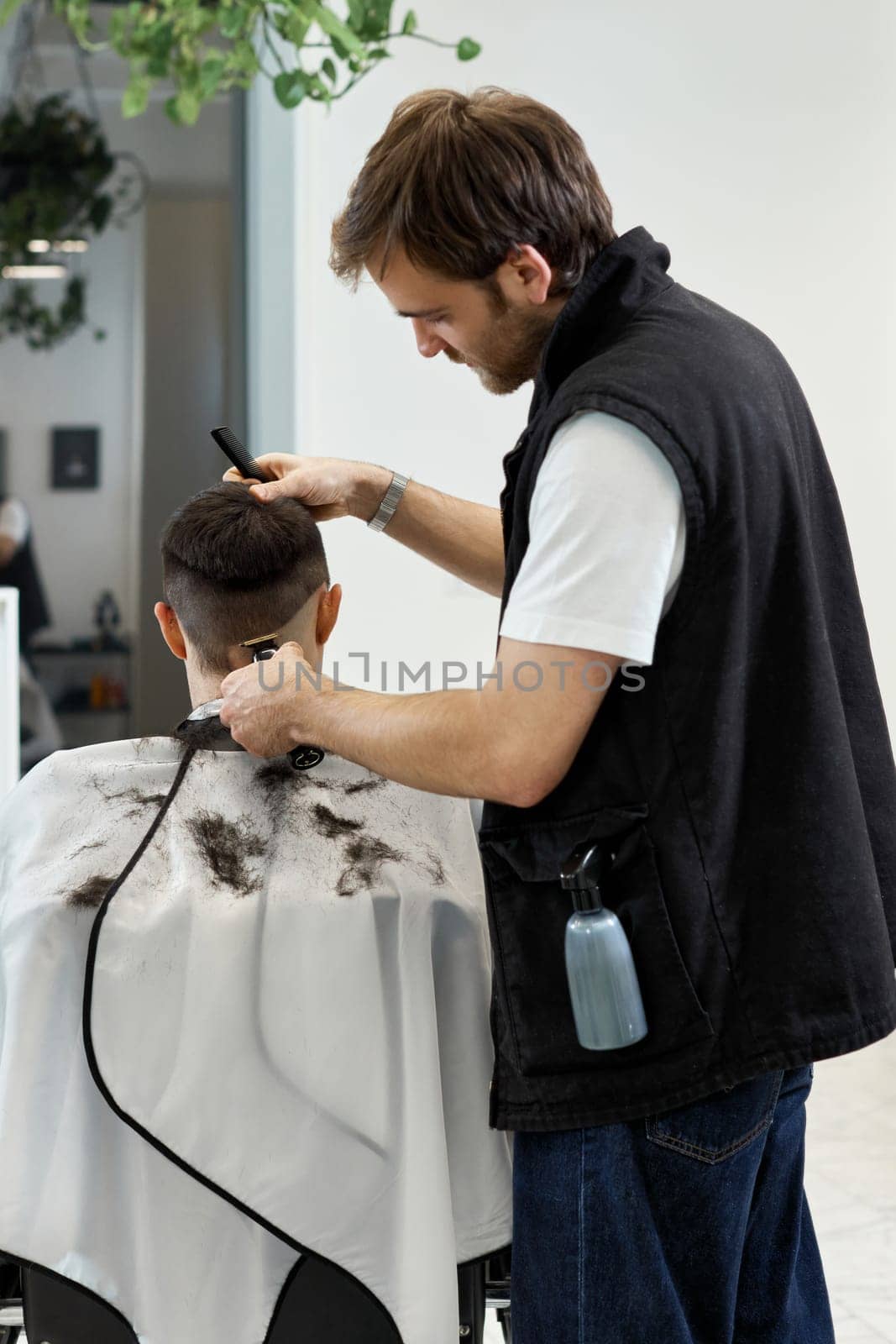 Barber shaving caucasian man in barber shop. by erstudio