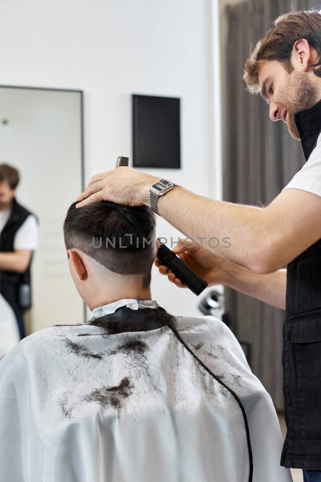 Barber trim hair with clipper on handsome man in barber shop.