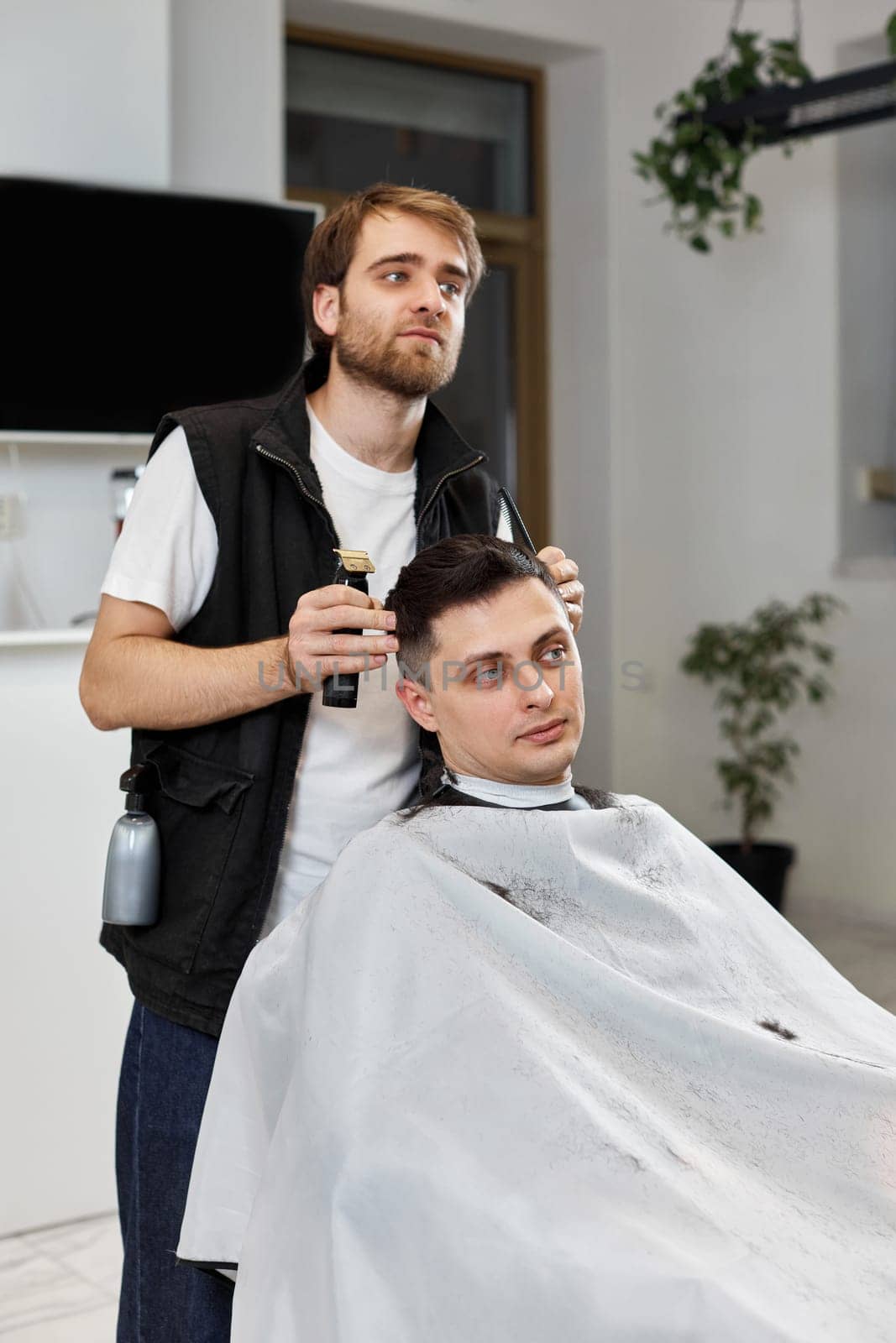 Barber shaving caucasian man in barber shop. by erstudio