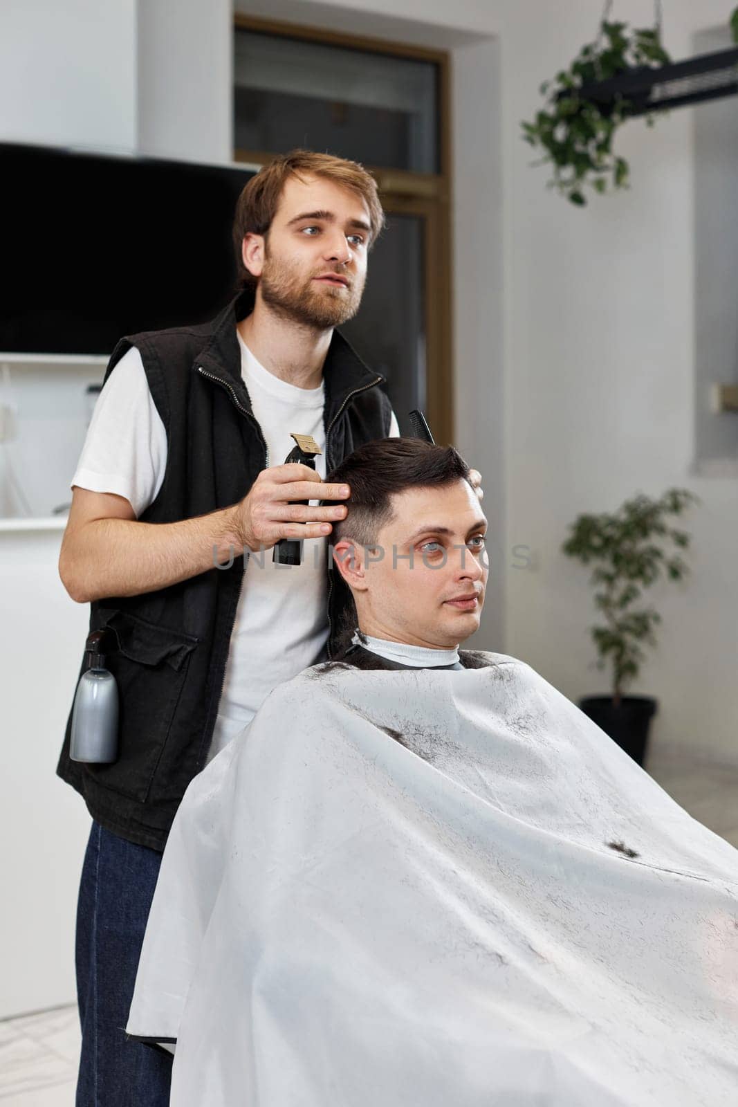 Barber shaving caucasian man in barber shop. by erstudio