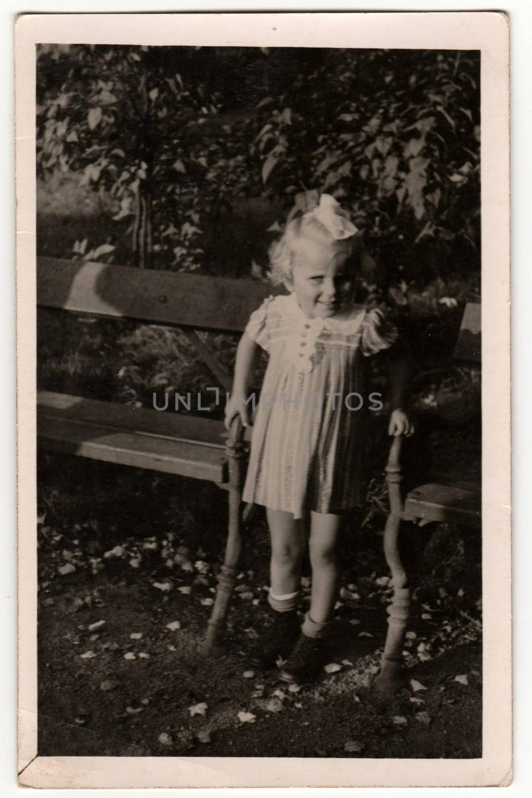 THE CZECHOSLOVAK REPUBLIC - SEPTEMBER 8, 1940: Vintage photo shows a small girl between park benches. Retro black and white photography.