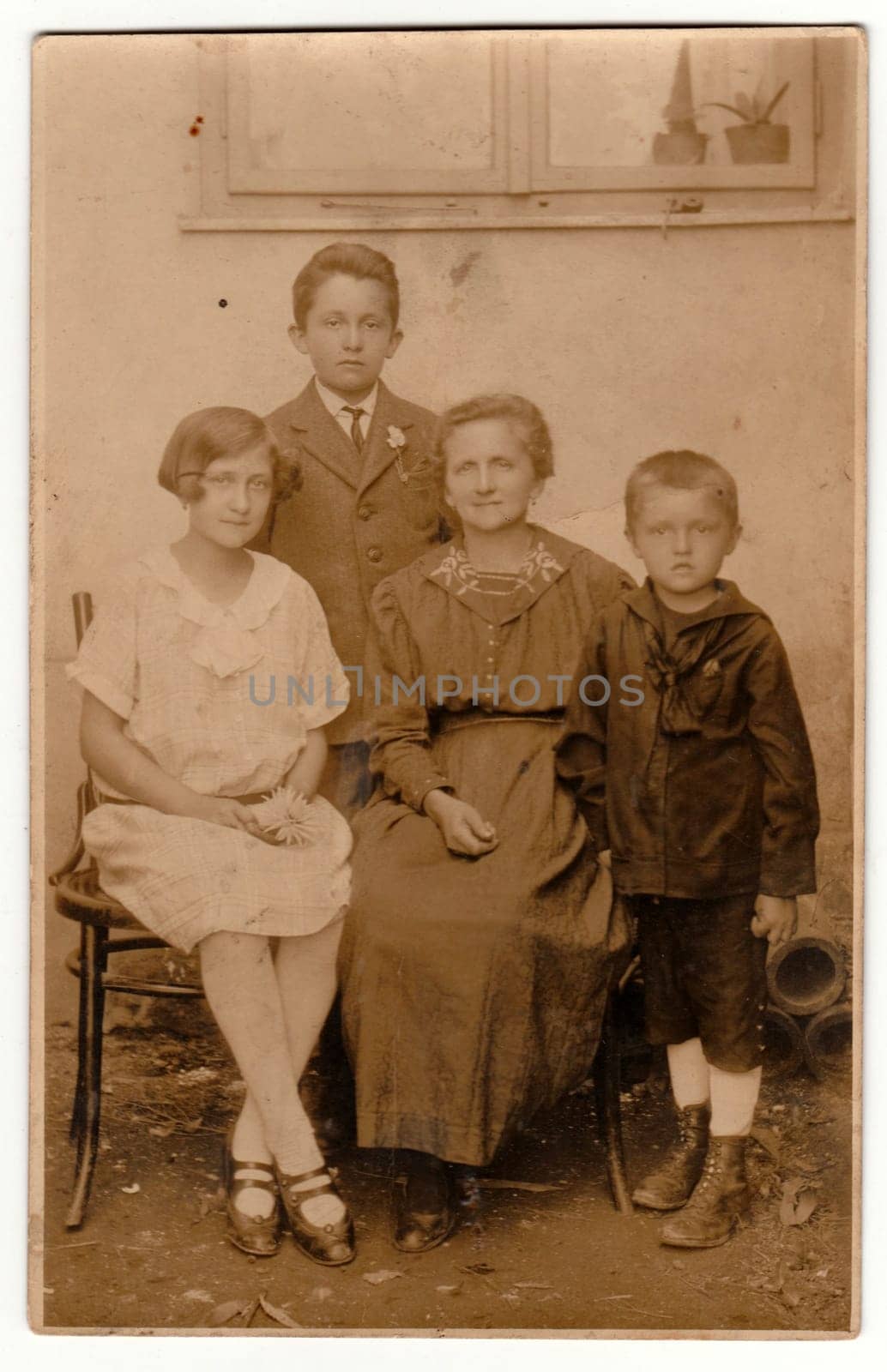 Vintage photo shows motther and her children pose outside. Retro black and white photography with sepia effect. by roman_nerud