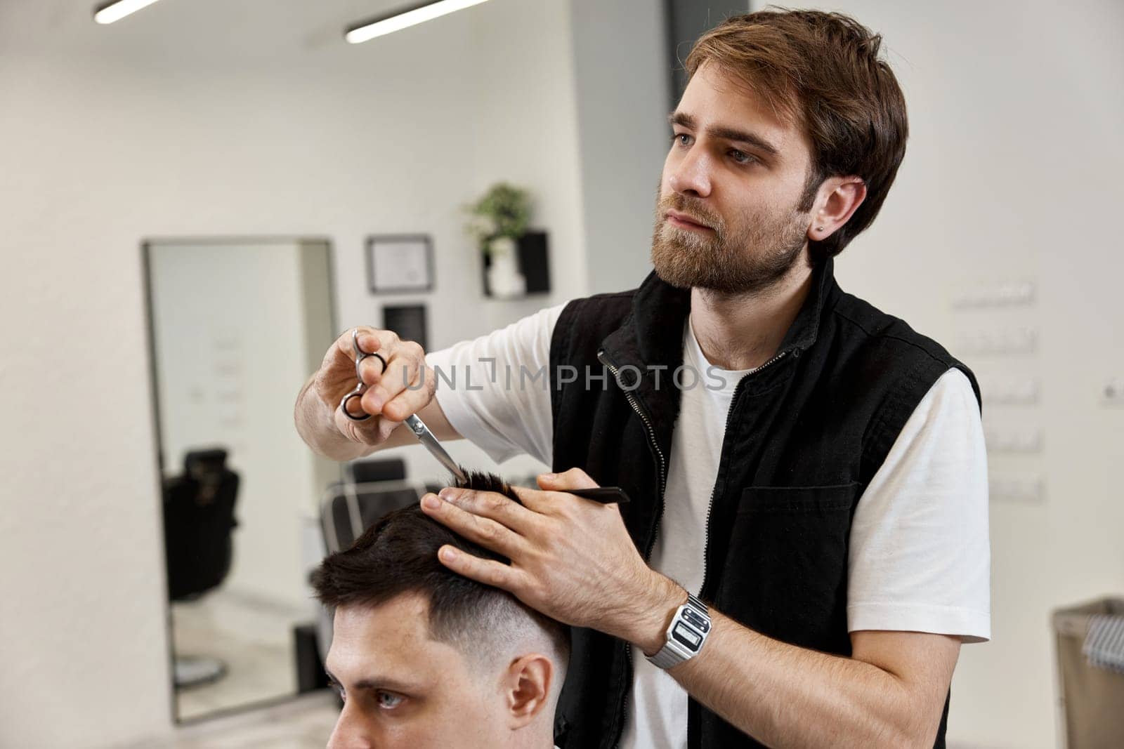 Professional hairdresser does haircut for caucasian bearded man by erstudio
