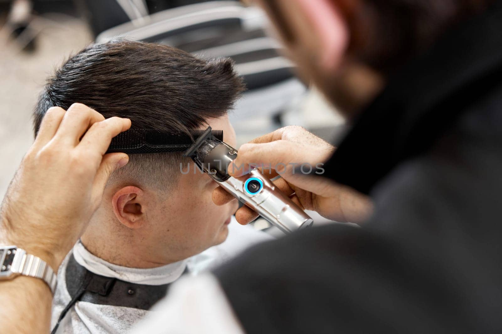 Barber shaving caucasian man in barber shop. by erstudio