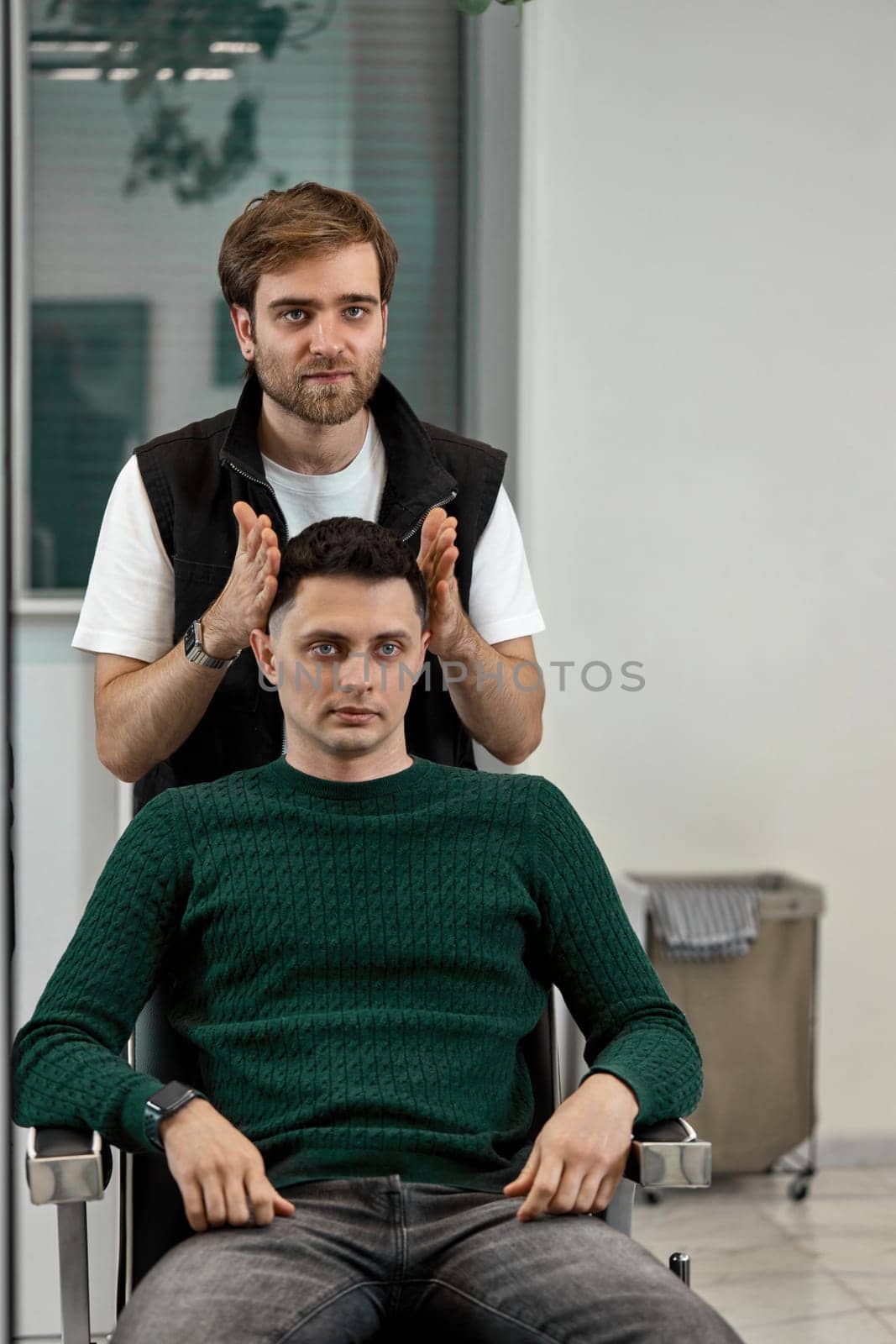 Barber and satisfied client man in front of the mirror in barber shop
