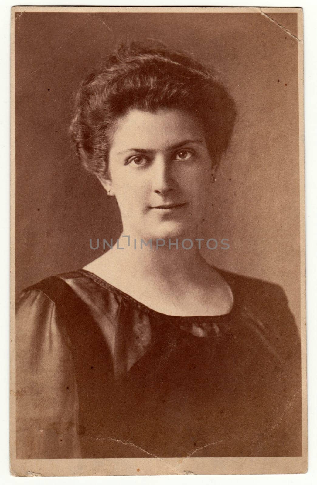 GERMANY - CIRCA 1930s: Vintage photo shows woman - portrait in a photography studio. Woman with Edwardian hairstyle. Retro black and white studio photography with sepia effect.