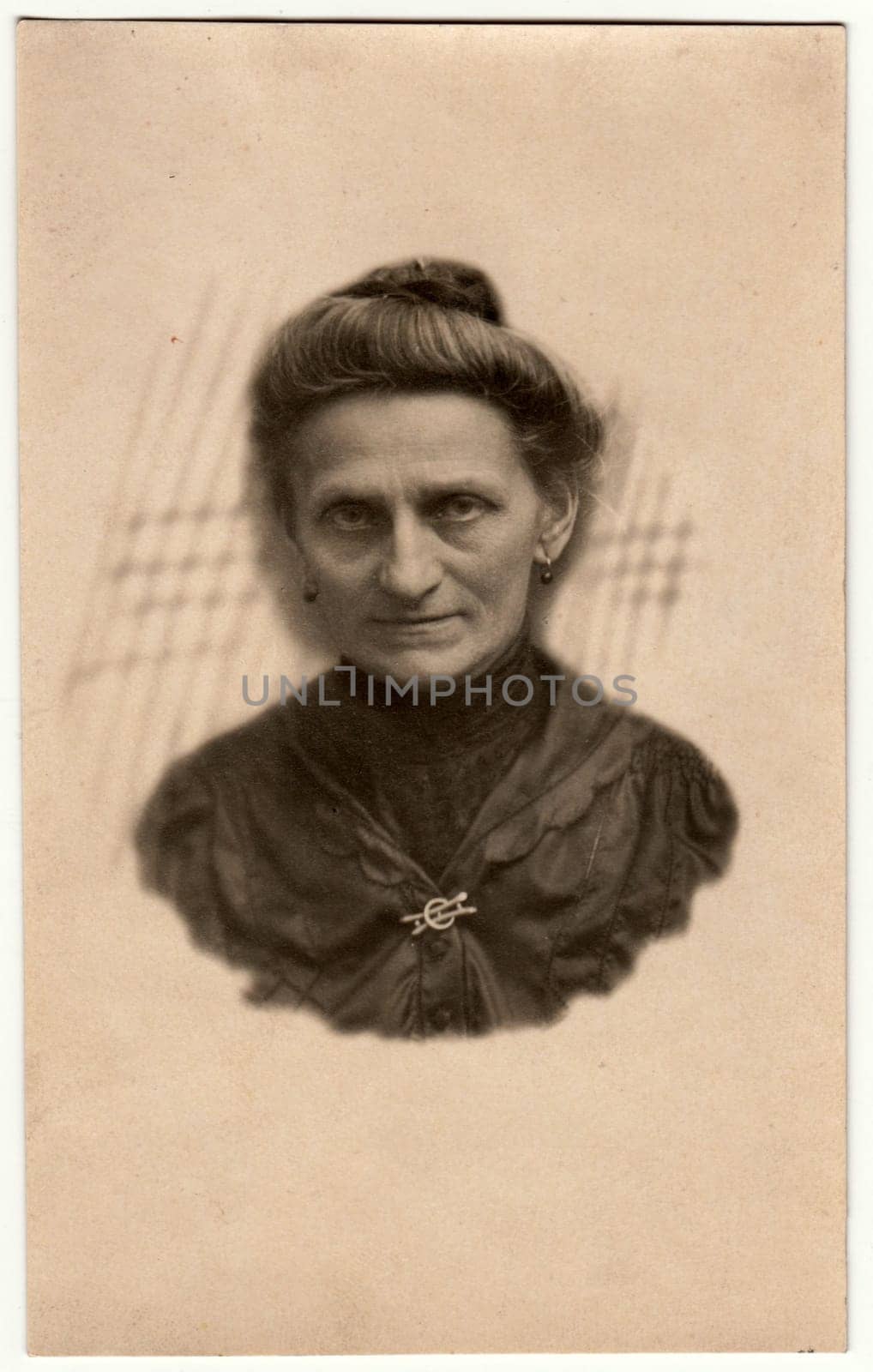 GERMANY - CIRCA 1930s: Vintage photo shows elderly woman - portrait in a photography studio. Woman with Edwardian hairstyle. Retro black and white studio photography with sepia effect. Head is drawn to body.