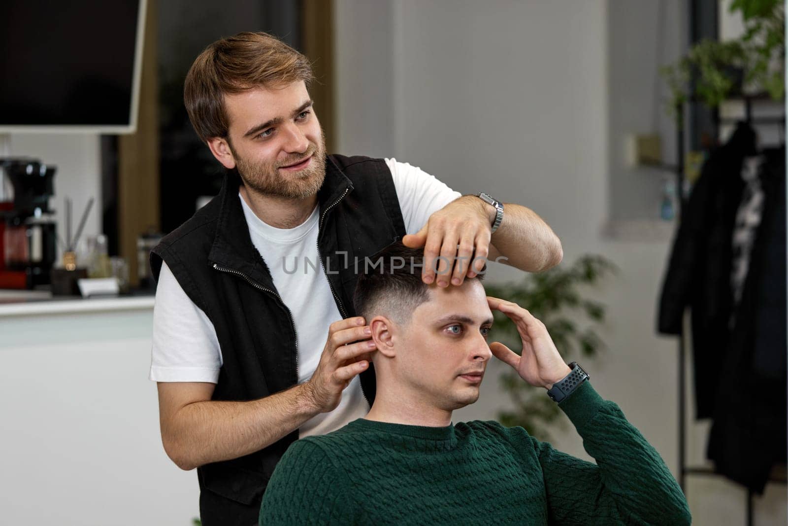 Barber and satisfied client man in front of the mirror in barber shop