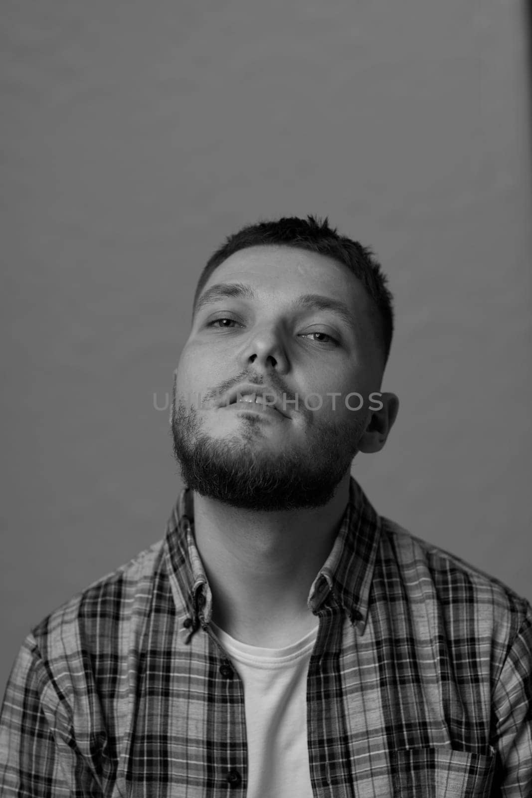 young bearded man looking at camera on gray background. black and white