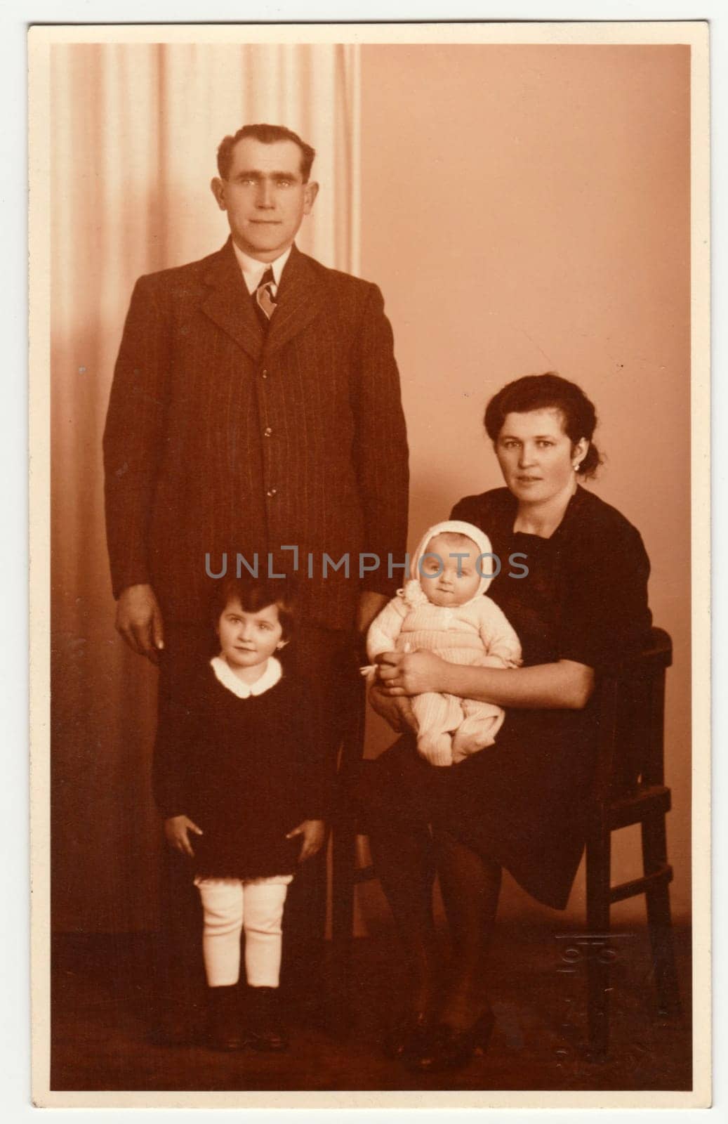 Vintage photo shows family in the photography studio. Retro black and white photography with sepia effect. by roman_nerud