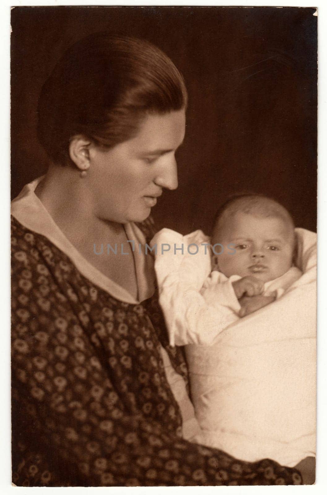 Vintage photo shows woman with baby - newborn in swaddling clothes. Retro black and white studio photography by roman_nerud