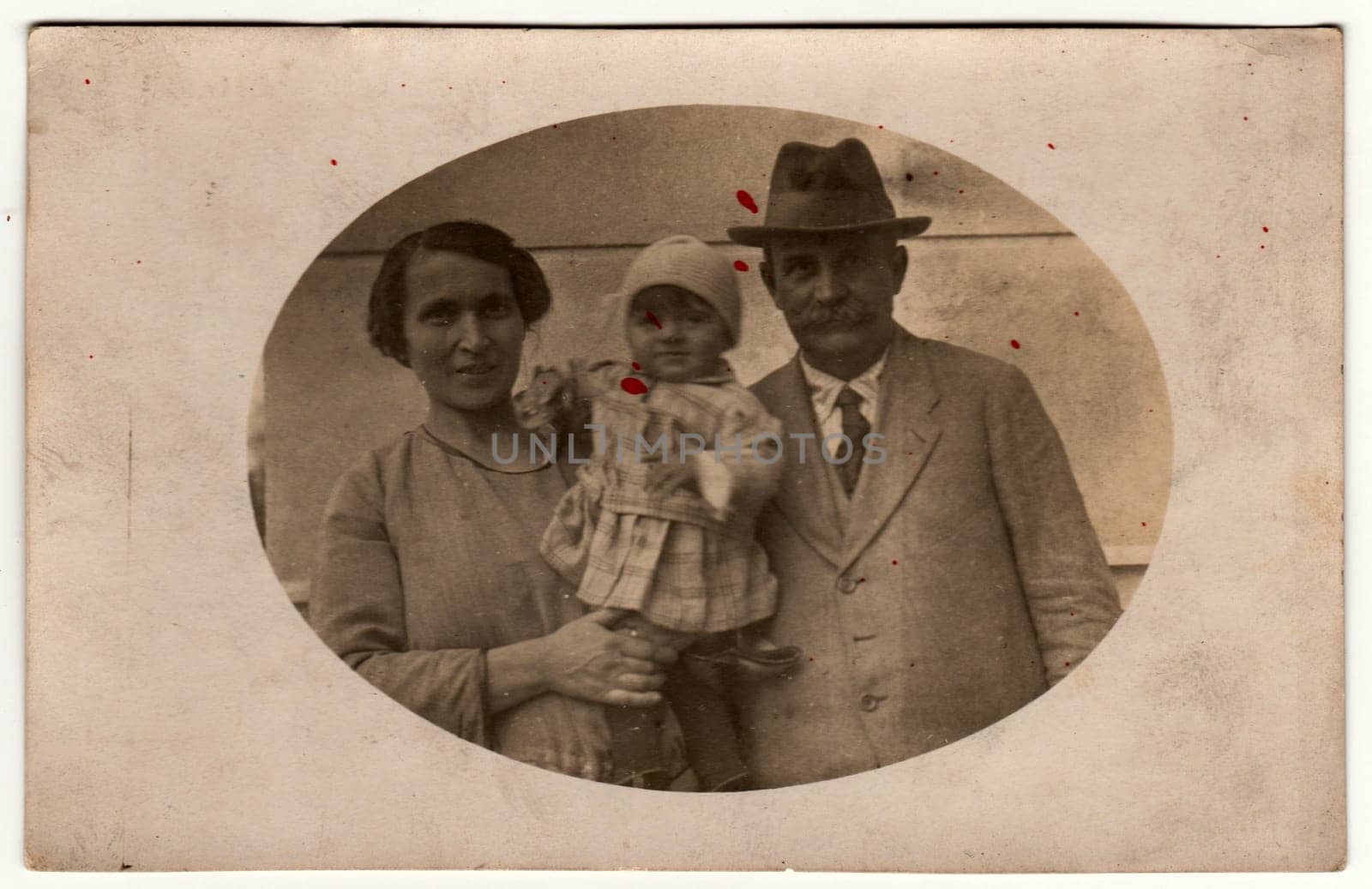 KOVCIN U OLSAN, THE CZECHOSLOVAK REPUBLIC - DECEMBER 20, 1923: Vintage photo shows mother holds a small baby and father. Retro black and white photography. Circa 1920.