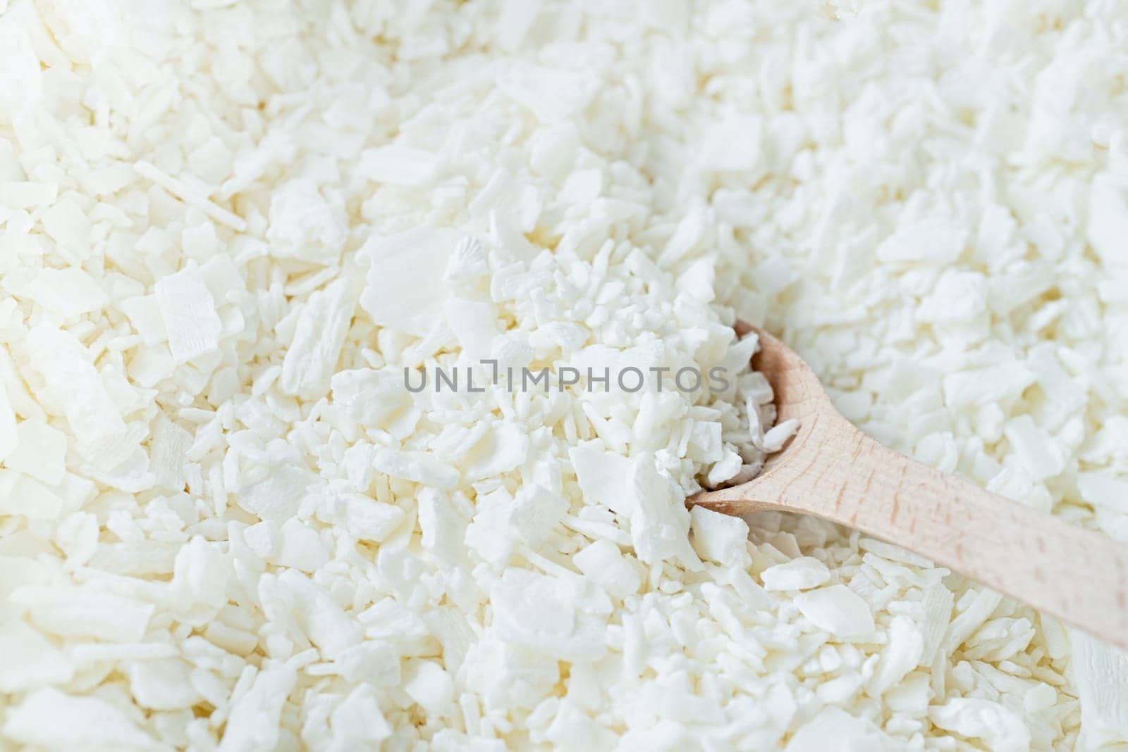 closeup of wooden spoon in white soy wax flakes by Desperada