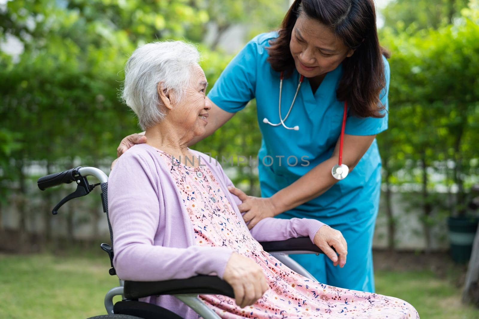 Doctor help and care Asian senior woman patient sitting on wheelchair at park in nursing hospital ward, healthy strong medical concept. by pamai