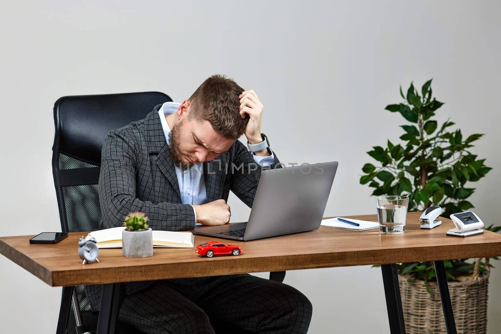 Exhausted tired man using laptop pc computer, sitting on chair at desk, having problems thinking about troubles