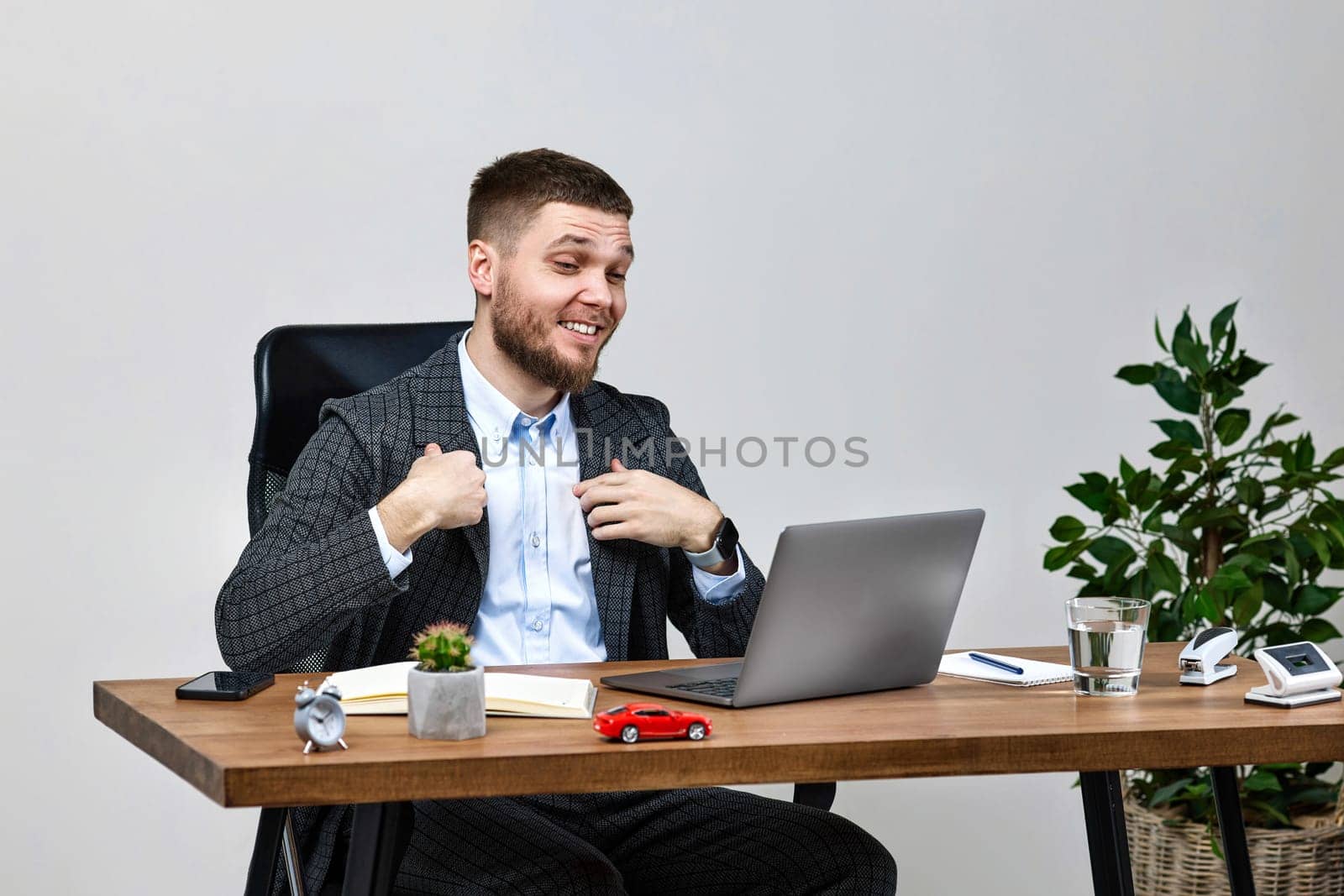 young friendly man talking on video call to client, sitting on chair at desk, using laptop pc computer