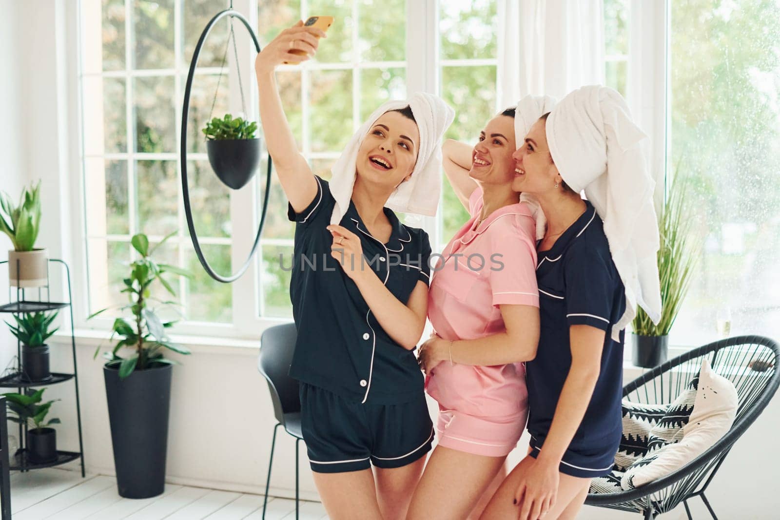 Cheerful young women in pajamas having fun indoors at daytime together by Standret