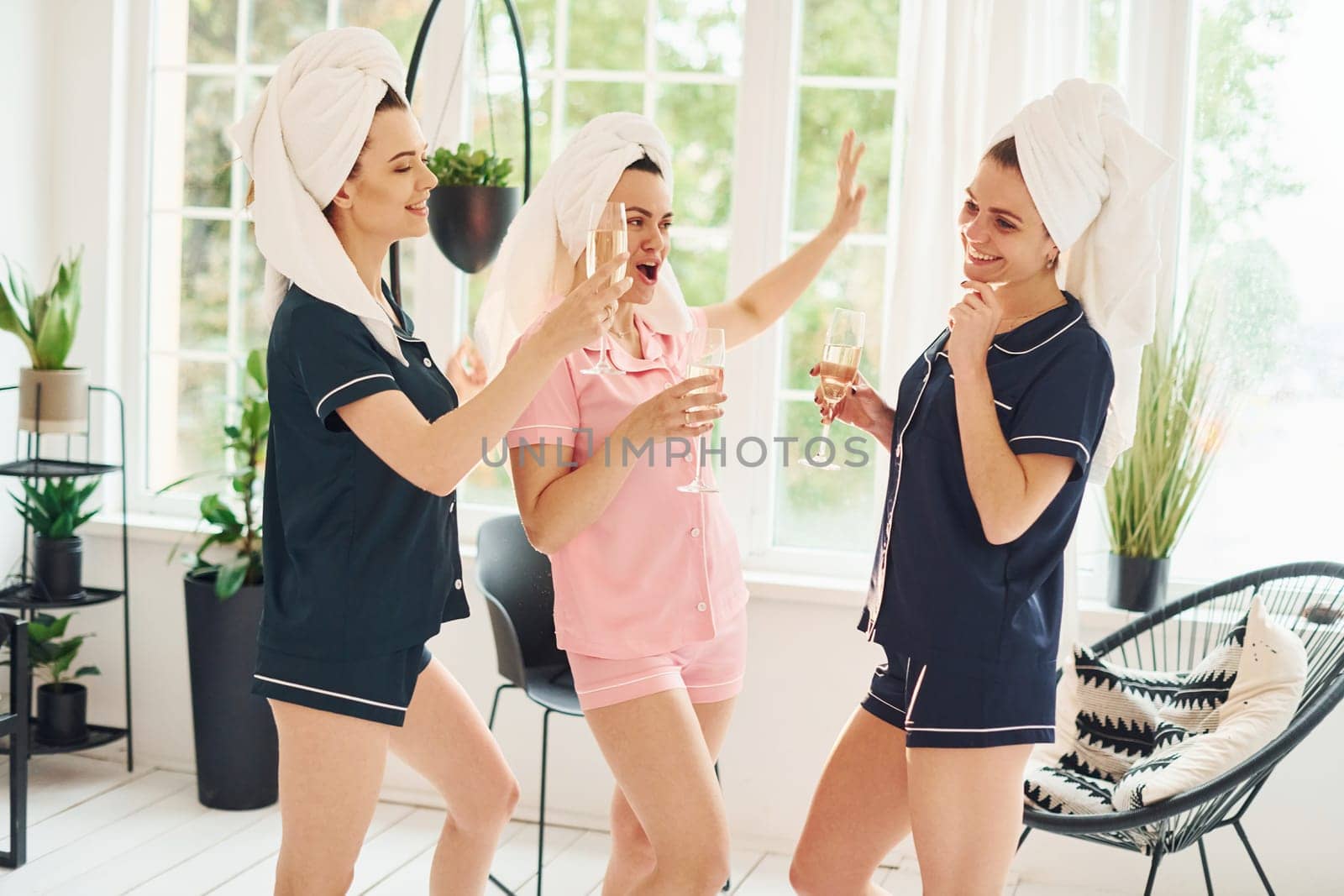 Cheerful young women in pajamas having fun indoors at daytime together.