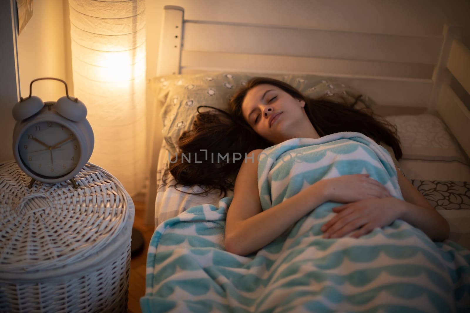 The young woman is lying on her back and her eyes are clouded. A girl under a soft blanket.