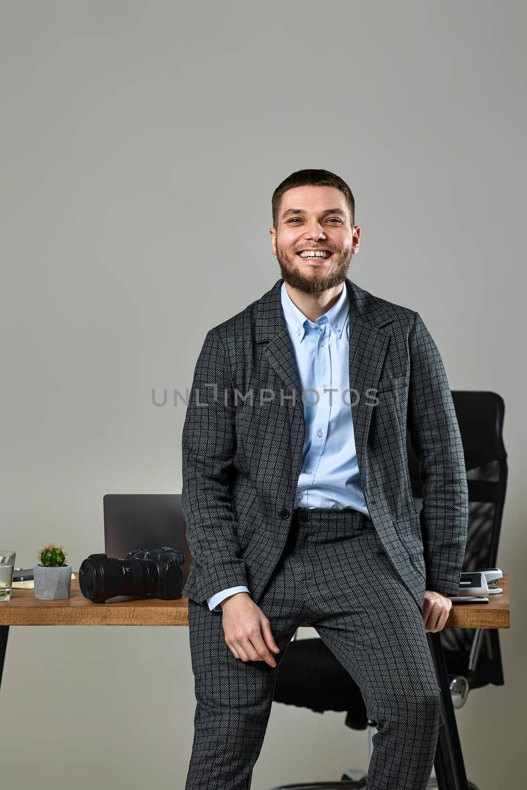 bearded man photographer smiling cheerfully while working at her desk.