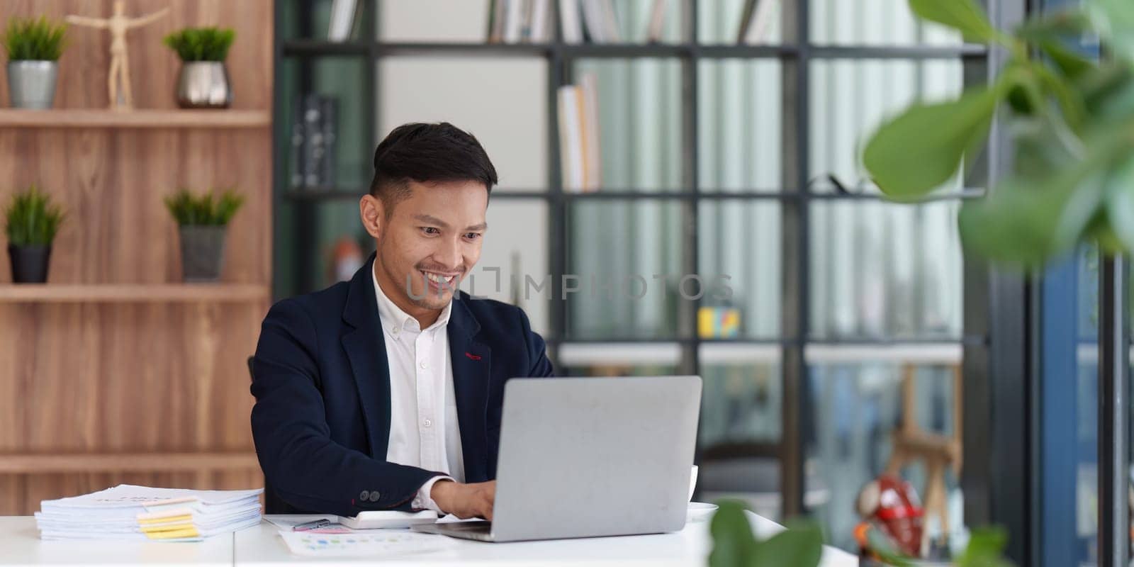 Smiling Asian Banker makes financial report and studies annual figures, analyzes profits. Accountant checks status of financial by itchaznong