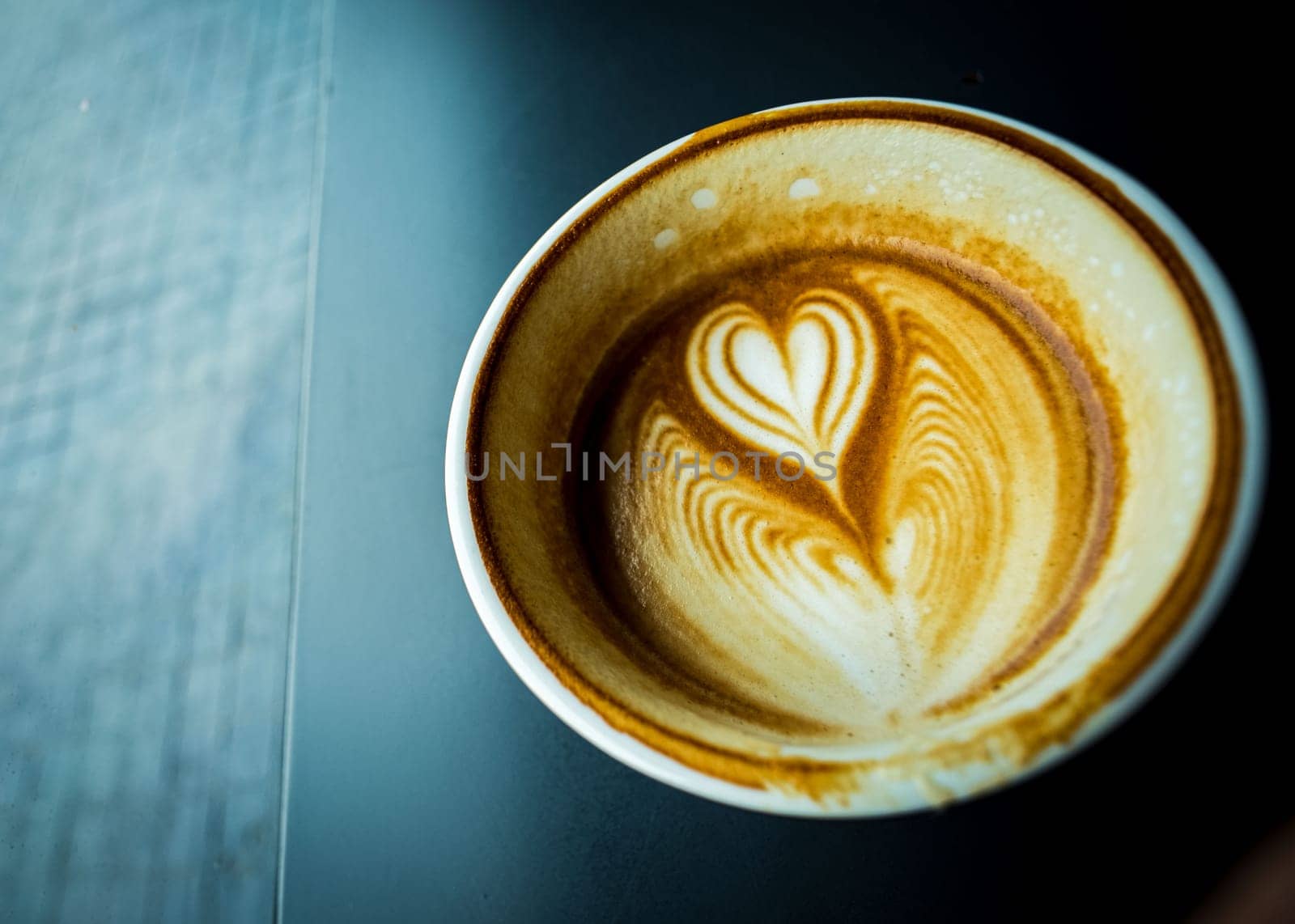 cup of hot latte coffee with love heart shape foam milk over dark background