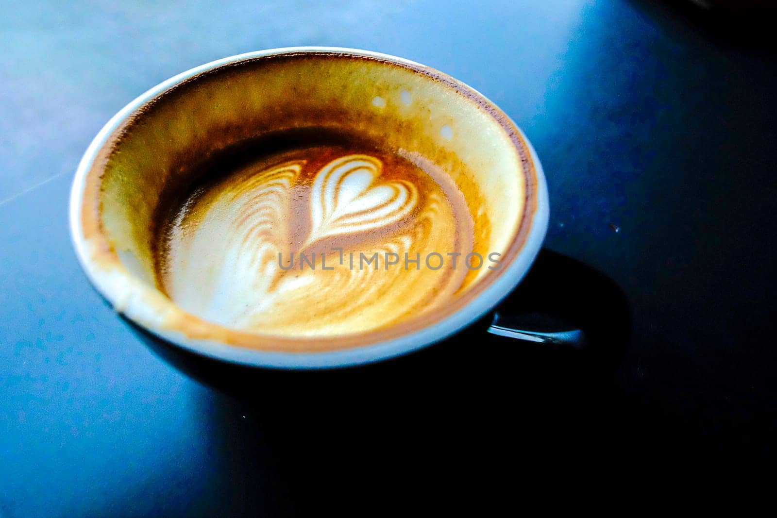 cup of hot latte coffee with love heart shape foam milk over dark background