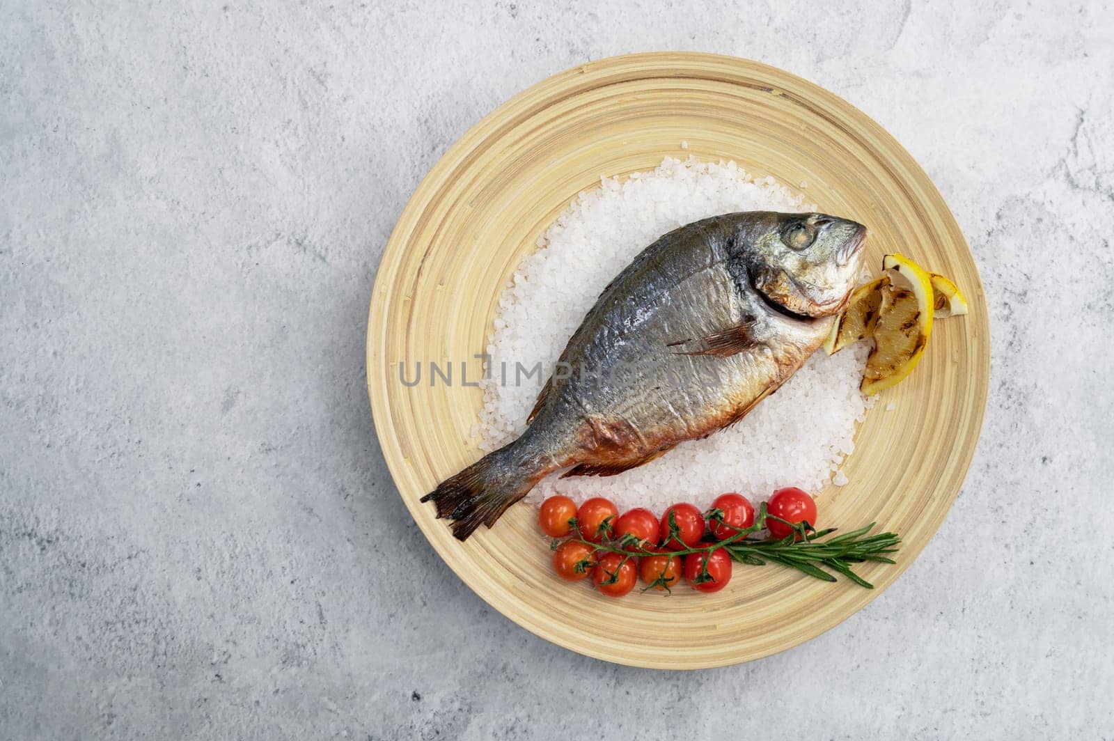Top view of plate with fresh grilled dorado fish with lemon and tomato