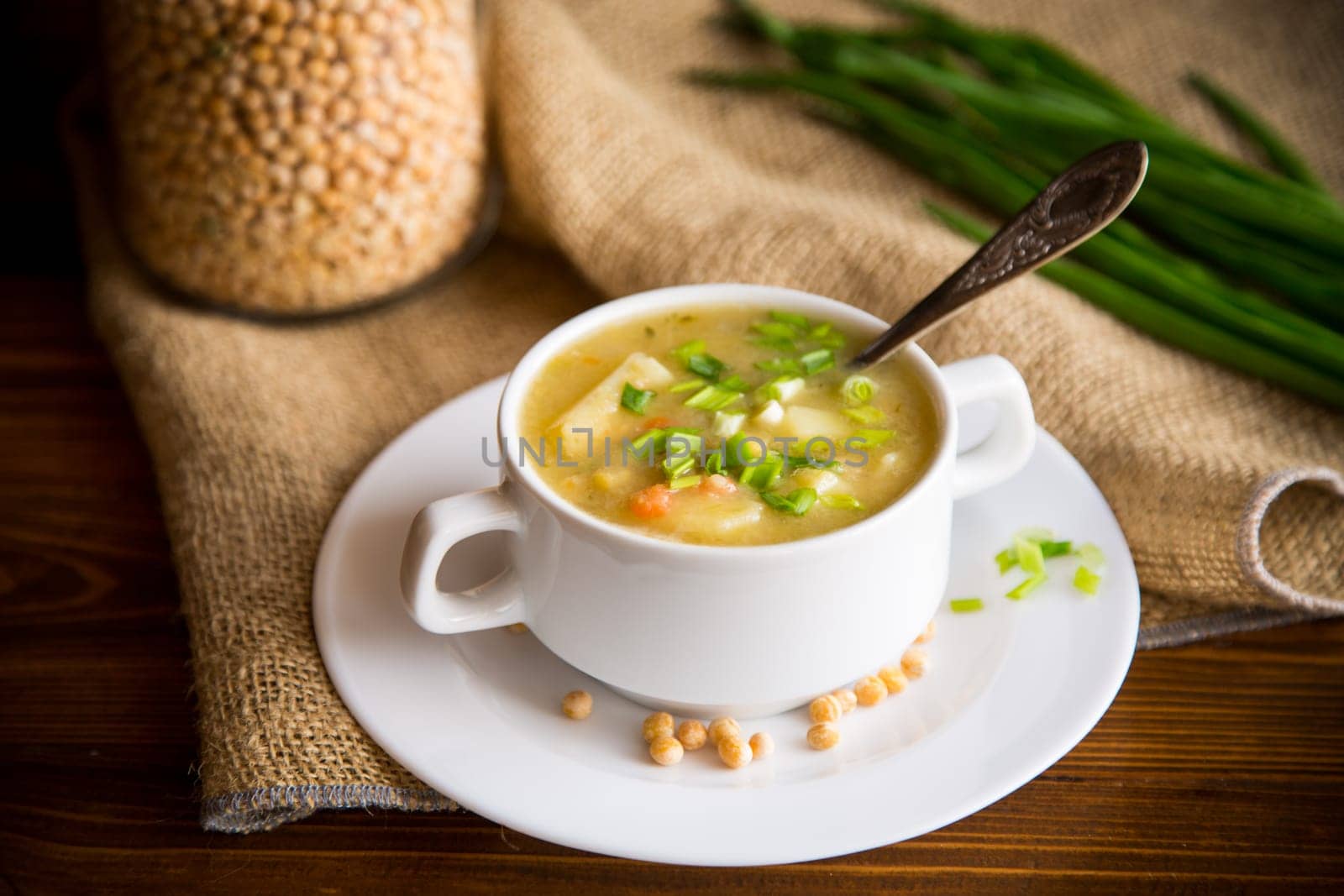 dried pea soup in a plate with herbs, on a wooden table.