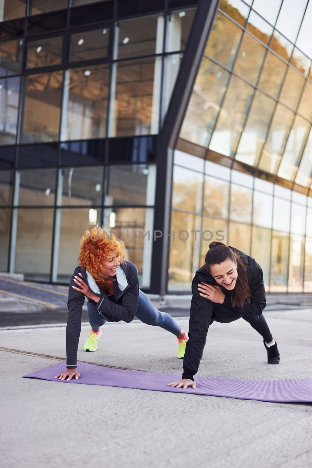 Doing push ups. Two female friends with sportive bodies have fitness day outdoors.