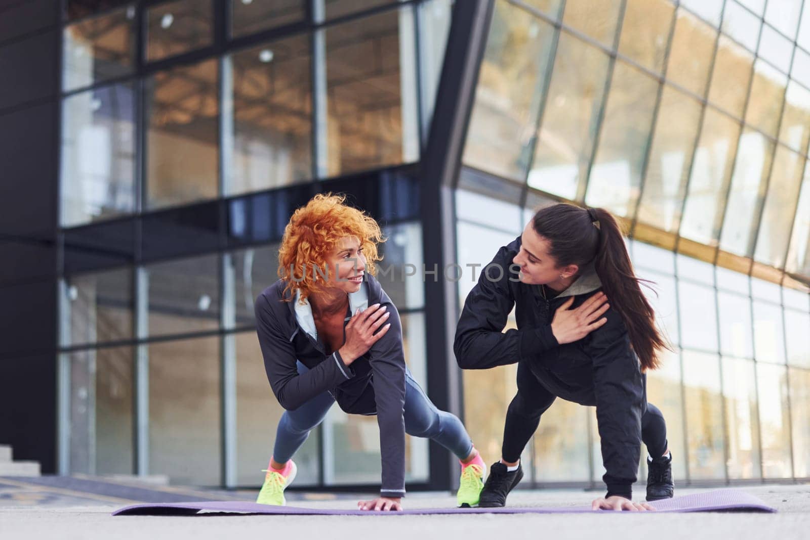 Doing push ups. Two female friends with sportive bodies have fitness day outdoors.