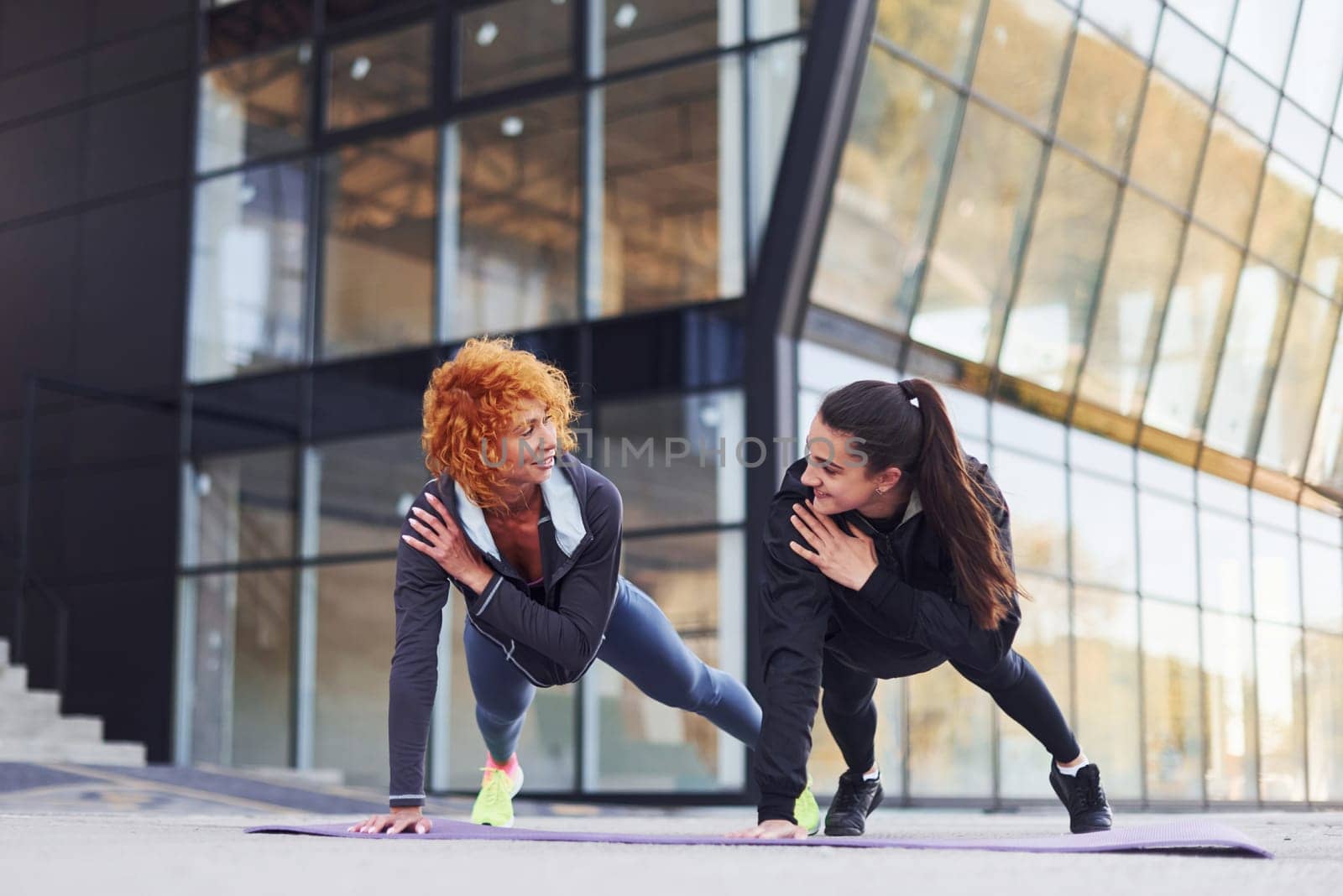 Doing push ups. Two female friends with sportive bodies have fitness day outdoors.