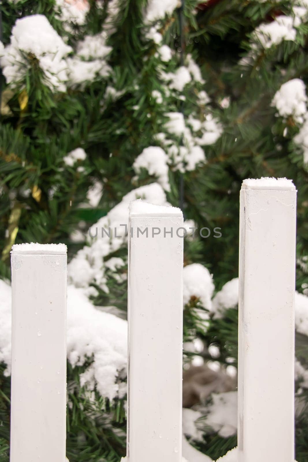 Snow on the white stakes of the fence close up