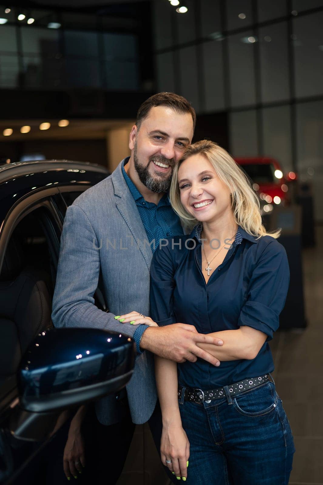 Portrait of a happy married couple in a car showroom. by mrwed54