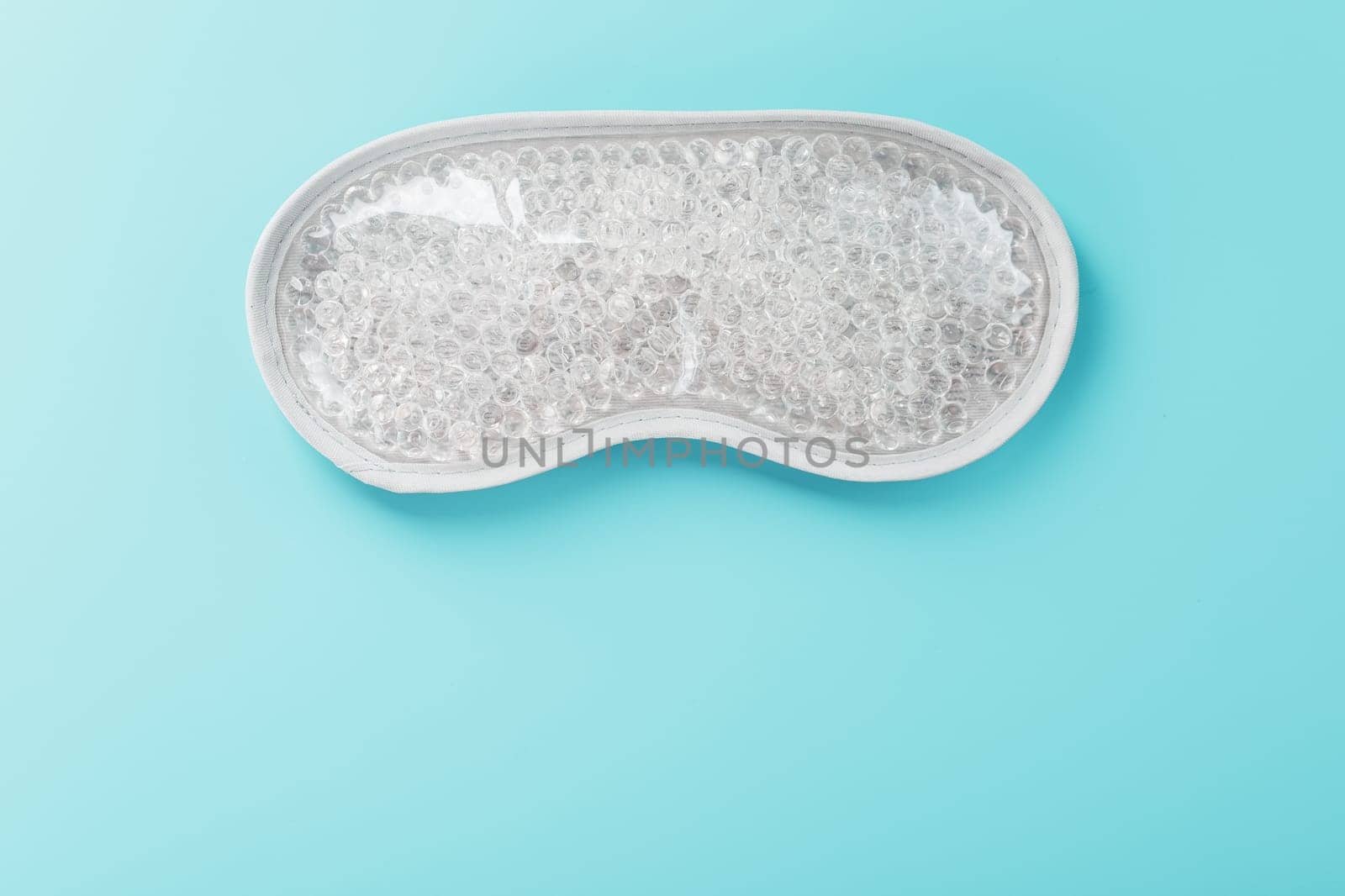 Eye mask with transparent gel balls inside on a blue background. A remedy for wrinkles and aging.