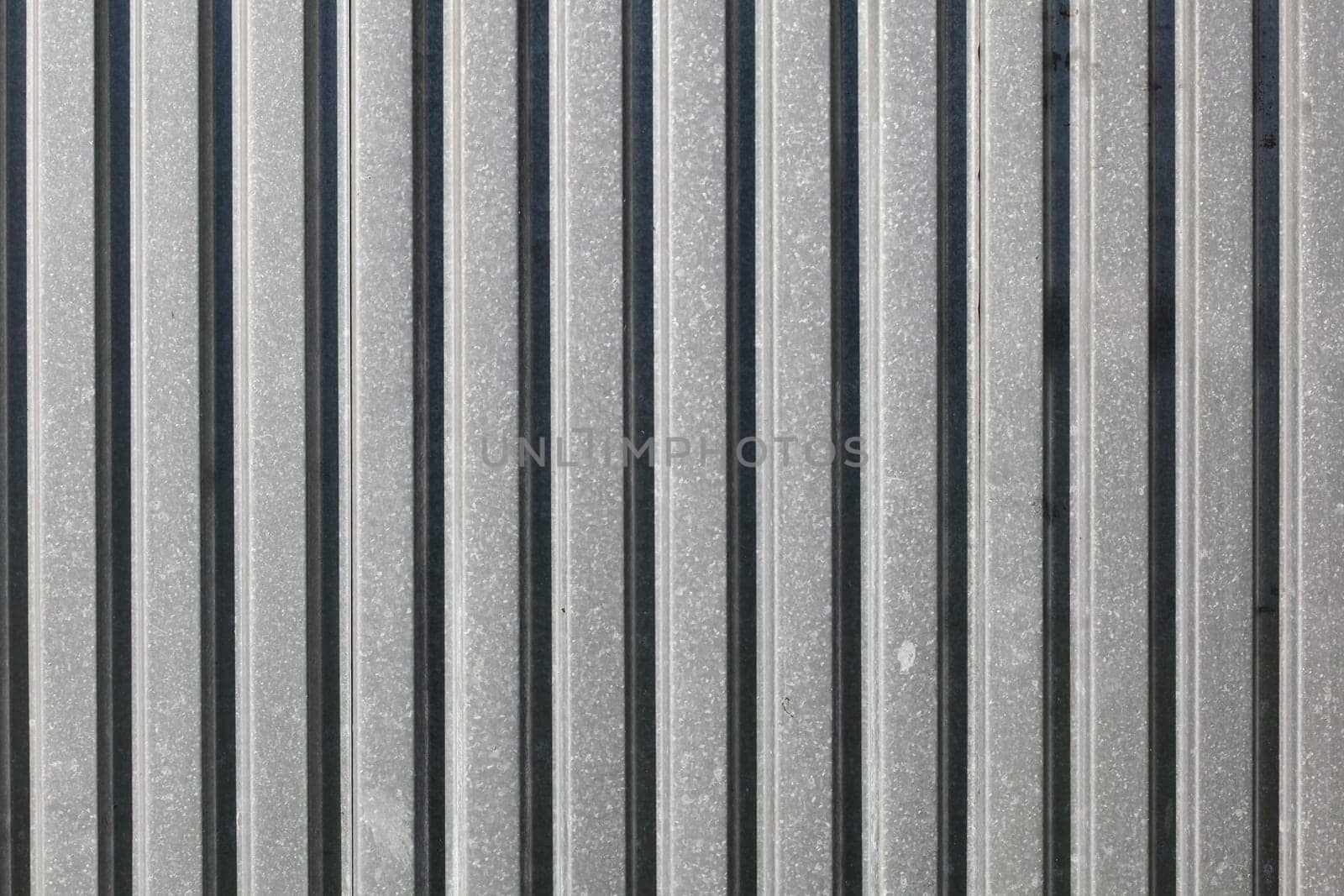 Metal plate fence, sun shining from side. Abstract construction background.