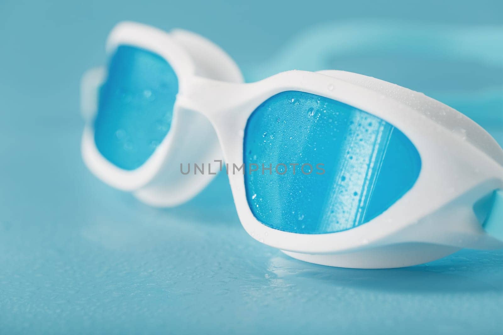 White swimming goggles on a blue background by AlexGrec