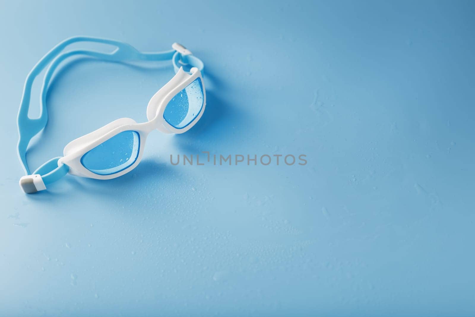 White swimming goggles on a blue background in a minimalist style with free space