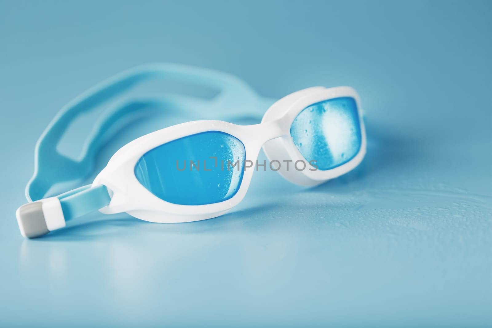 Swimming goggles in a white frame with a blue filter on a blue background