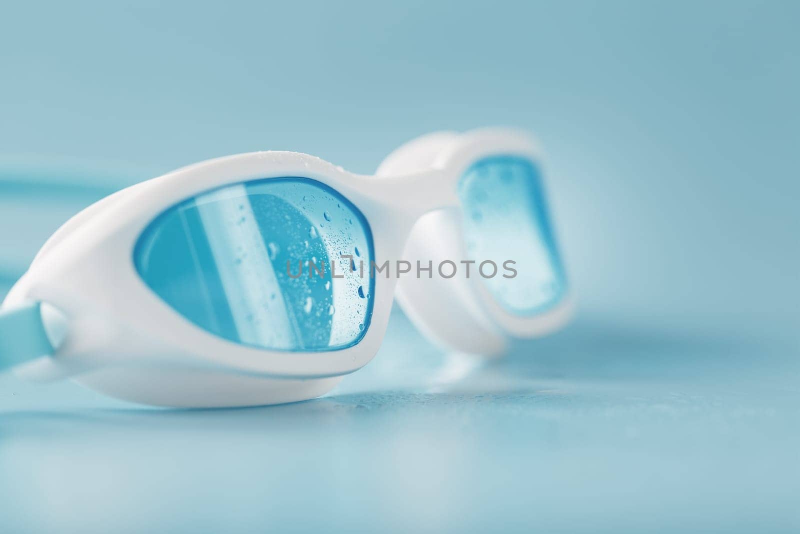 Swimming goggles in a white frame with a blue filter on a blue background