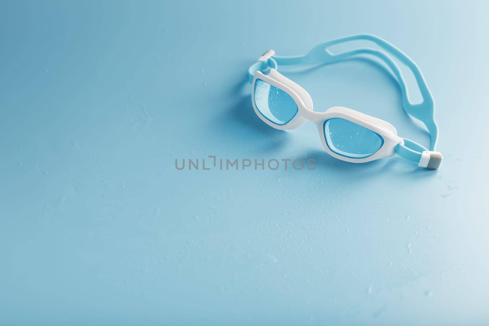 Swimming goggles in a white frame with on a blue background by AlexGrec