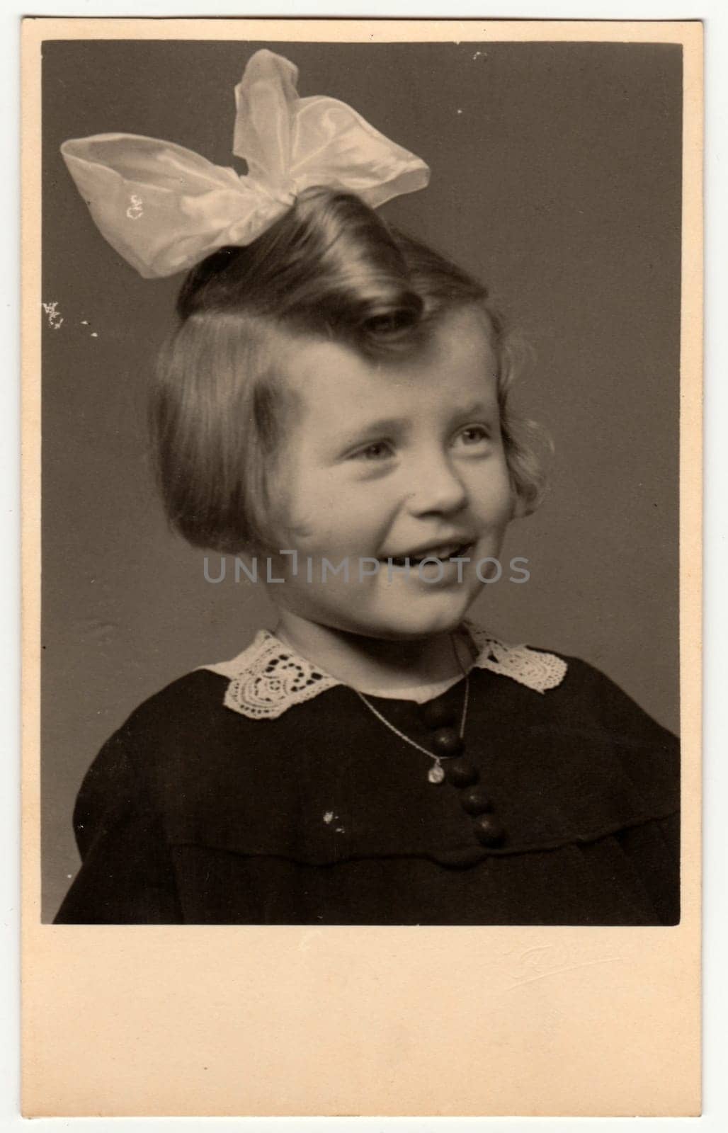 THE CZECHOSLOVAK REPUBLIC - CIRCA 1950s: Vintage photo shows a portrait of a small cute girl with ribbon in hair. Retro black and white photography. Circa 1950s.