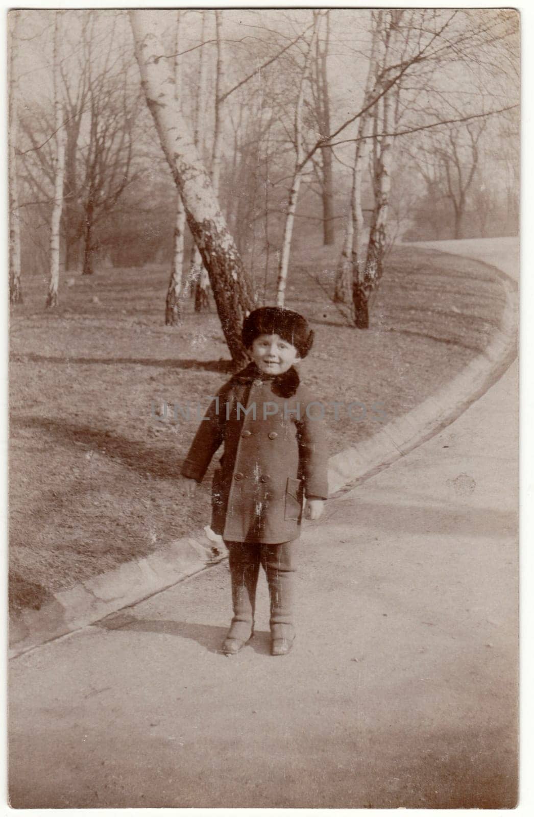 Vintage photo shows a small cute boy wears fur cap - Cossack hat. Retro black and white photography. Circa 1950s. by roman_nerud