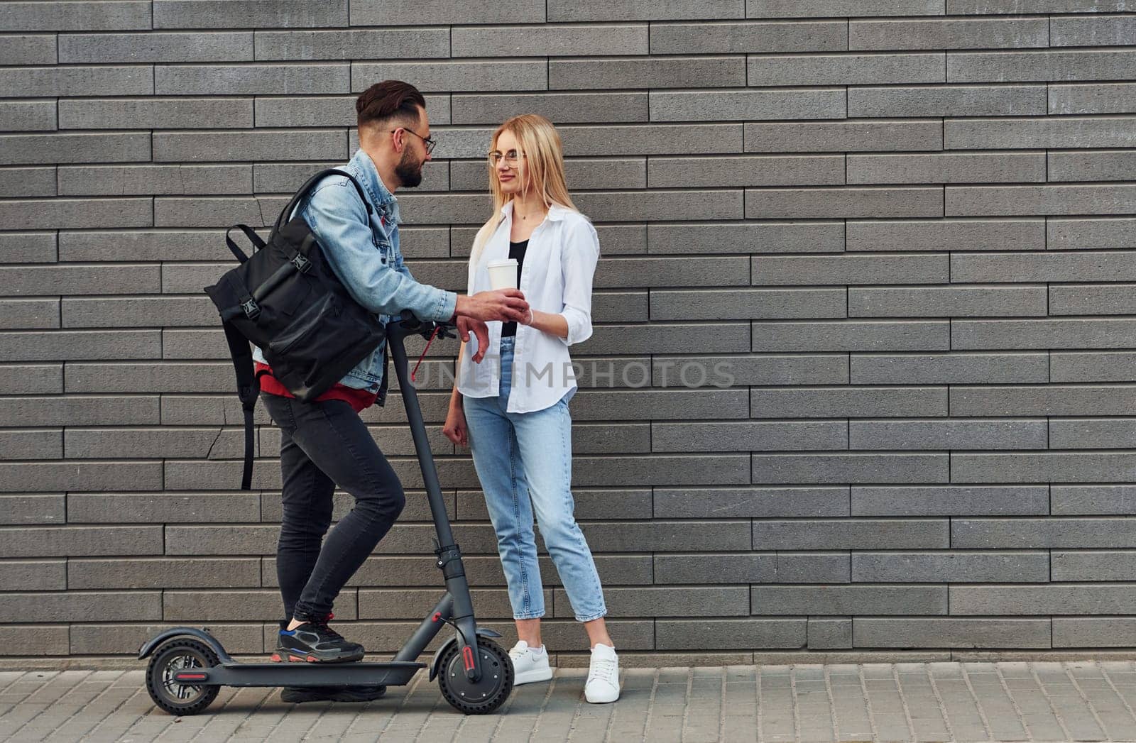 With electric schooter. Young stylish man with woman in casual clothes outdoors together. Conception of friendship or relationships.