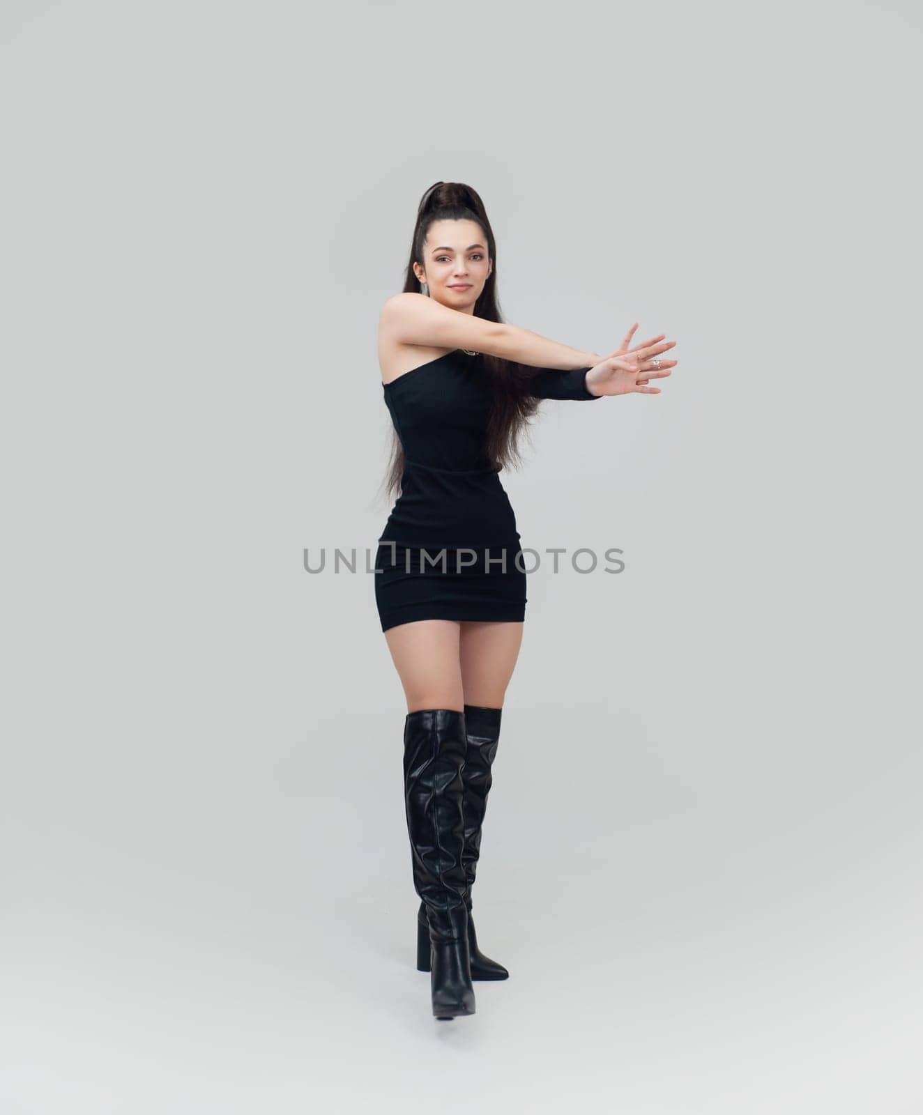 sexy girl in a short black dress and high boots on a light empty background of copy paste