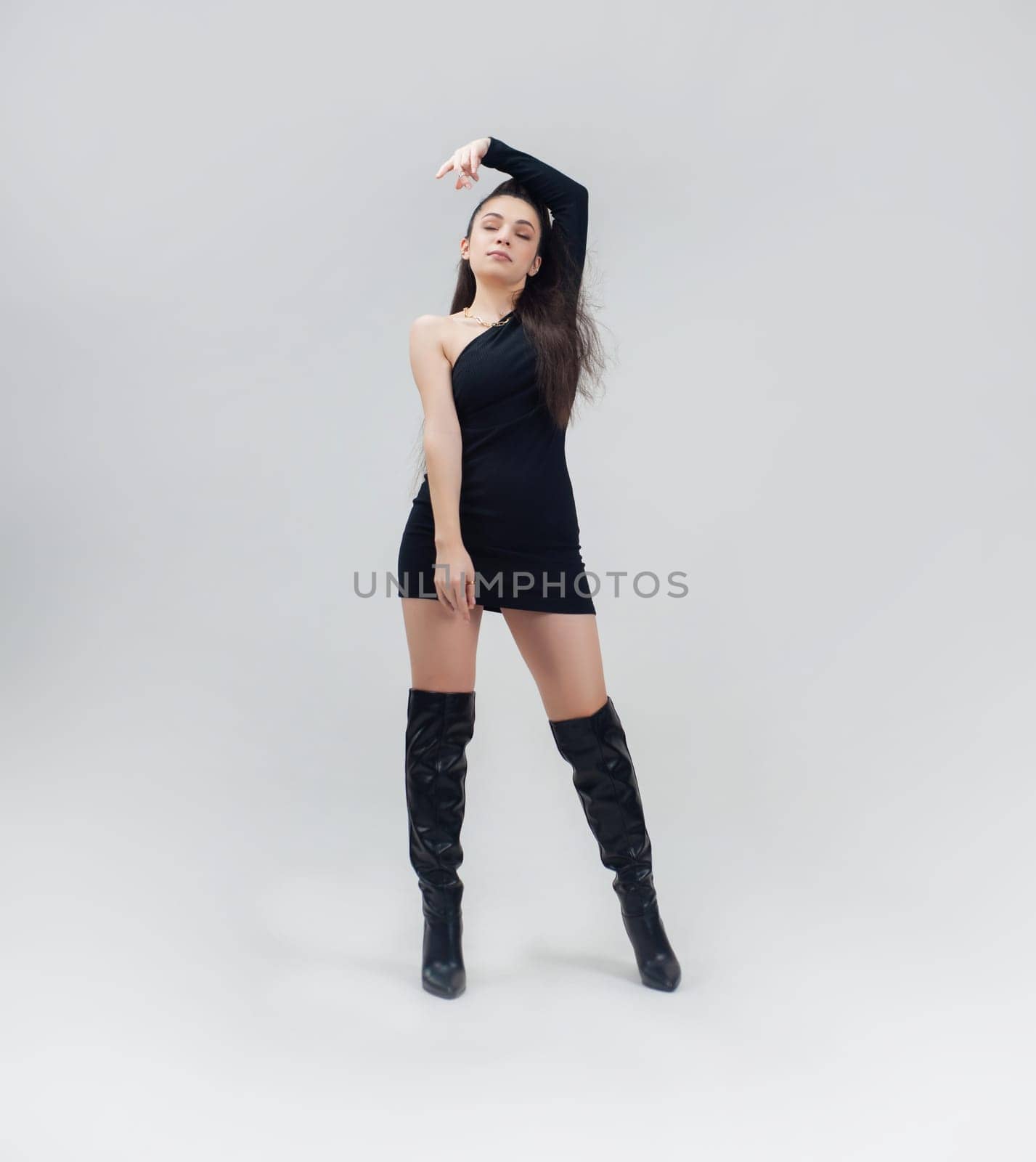 sexy girl in a short black dress and high boots on a light empty background of copy paste